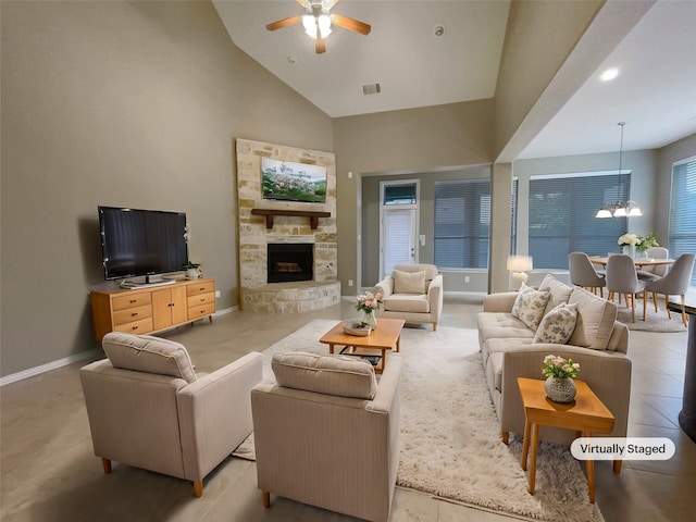 living room with a stone fireplace, high vaulted ceiling, and ceiling fan with notable chandelier