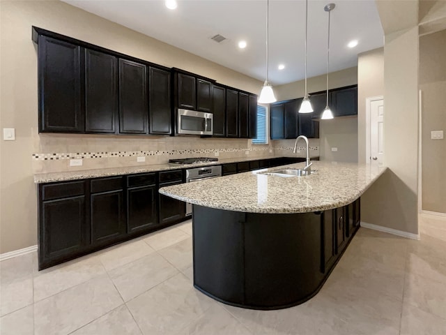 kitchen featuring light stone countertops, sink, stainless steel appliances, tasteful backsplash, and pendant lighting