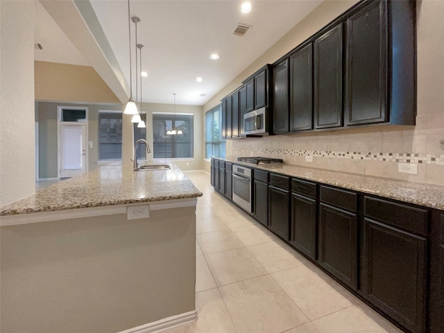 kitchen featuring appliances with stainless steel finishes, sink, pendant lighting, and an island with sink