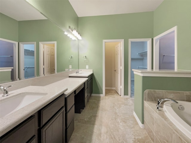 bathroom featuring tiled bath, tile patterned flooring, and vanity