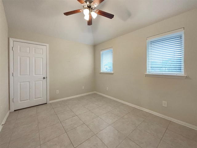 empty room featuring ceiling fan, a healthy amount of sunlight, and light tile patterned floors