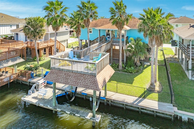 view of dock with a deck with water view and a lawn