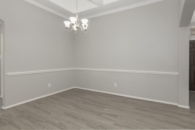 spare room featuring ornamental molding, hardwood / wood-style floors, and a notable chandelier