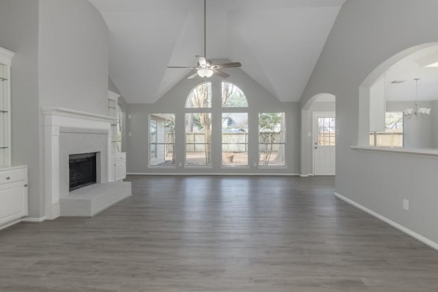 unfurnished living room with ceiling fan with notable chandelier, hardwood / wood-style flooring, and vaulted ceiling