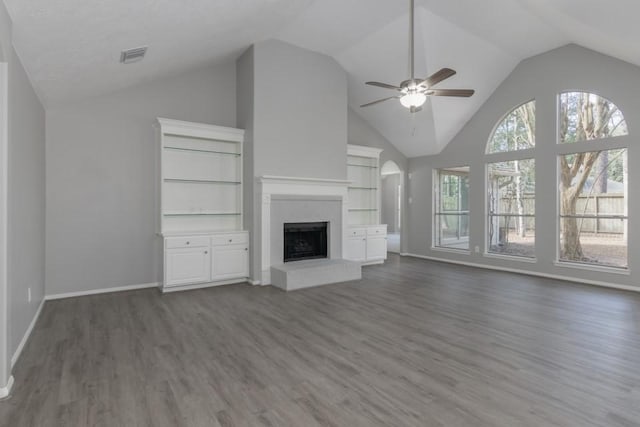 unfurnished living room featuring ceiling fan, lofted ceiling, a fireplace, dark hardwood / wood-style floors, and built in features