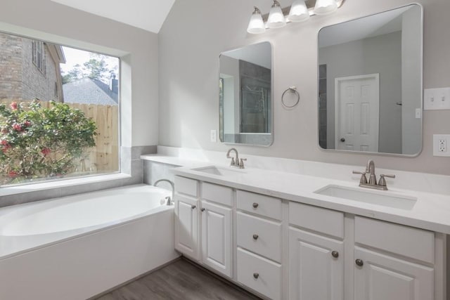 bathroom with a bathing tub, lofted ceiling, hardwood / wood-style flooring, and vanity