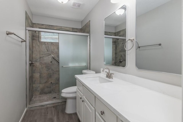 bathroom featuring vanity, toilet, hardwood / wood-style floors, and walk in shower