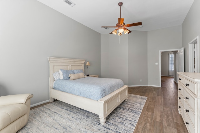 bedroom featuring dark wood-type flooring, visible vents, baseboards, and a ceiling fan