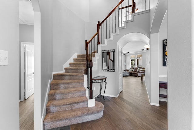 staircase featuring ceiling fan, wood-type flooring, and a high ceiling