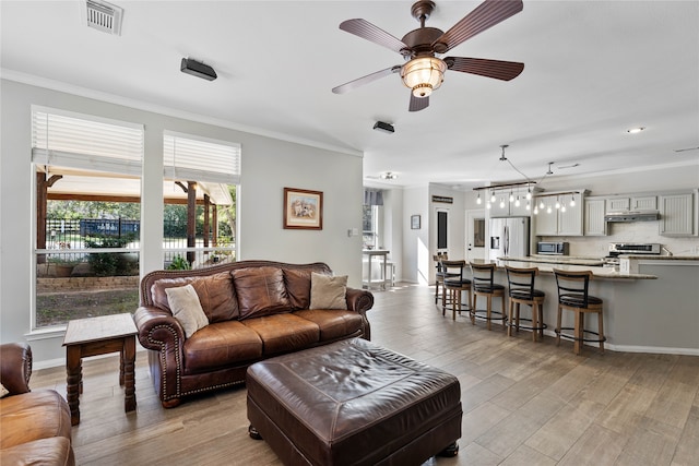 living room with ceiling fan, light hardwood / wood-style flooring, and ornamental molding