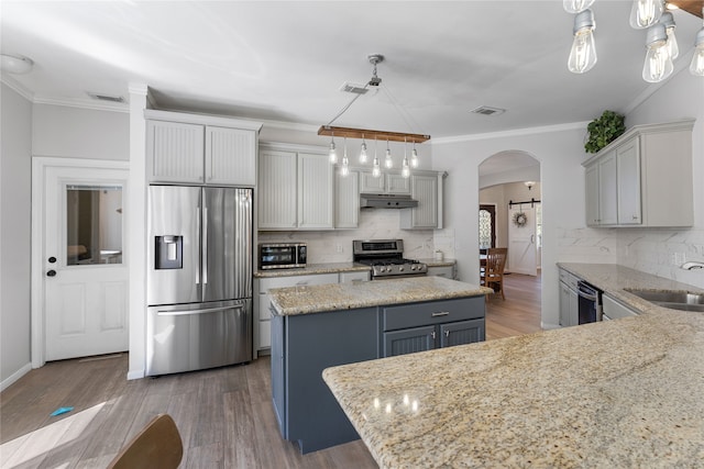 kitchen featuring arched walkways, a kitchen island, appliances with stainless steel finishes, gray cabinets, and pendant lighting