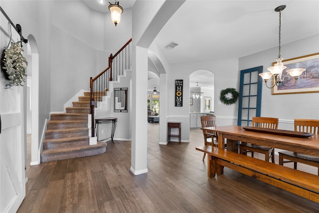 dining space with a barn door, an inviting chandelier, and dark wood-type flooring