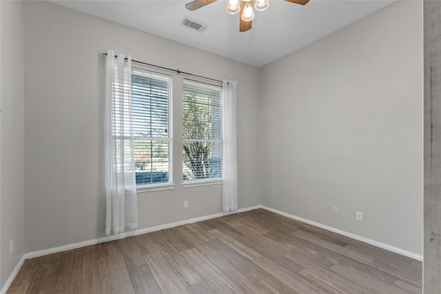 unfurnished room with wood finished floors, visible vents, and baseboards