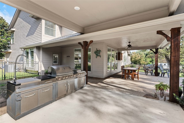 view of patio with ceiling fan, a grill, fence, exterior kitchen, and outdoor dining space