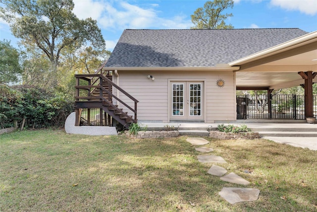 rear view of house with a shingled roof, a yard, and stairway