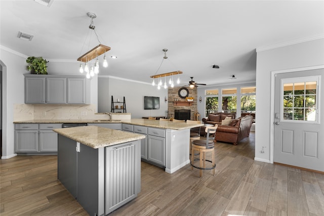 kitchen with a center island, hanging light fixtures, gray cabinetry, open floor plan, and a peninsula