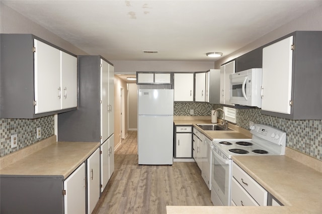 kitchen with white cabinetry, white appliances, sink, and light hardwood / wood-style flooring