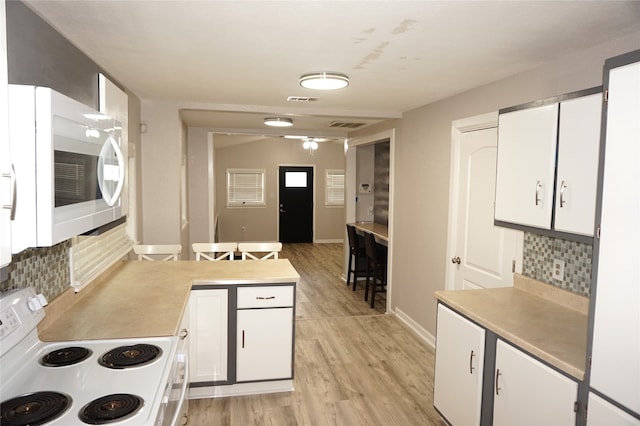 kitchen with backsplash, white cabinetry, light hardwood / wood-style floors, and white appliances