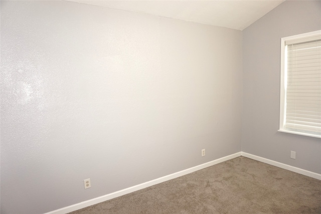 unfurnished room featuring lofted ceiling and carpet floors