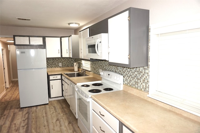 kitchen with decorative backsplash, white appliances, sink, hardwood / wood-style floors, and white cabinetry