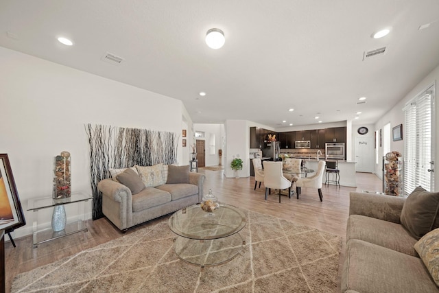 living room with light hardwood / wood-style flooring and sink