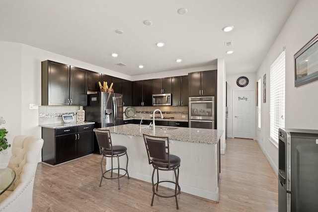 kitchen featuring decorative backsplash, light hardwood / wood-style floors, sink, and appliances with stainless steel finishes