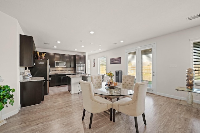 dining space with light wood-type flooring and a healthy amount of sunlight