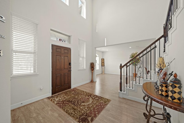 entrance foyer with light wood-type flooring and a towering ceiling