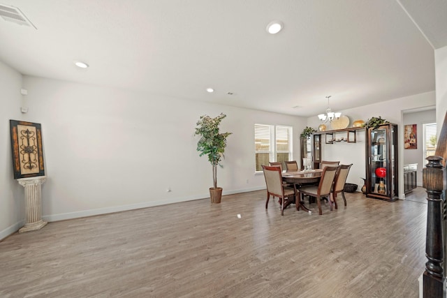 dining room featuring light wood-type flooring, an inviting chandelier, and a wealth of natural light