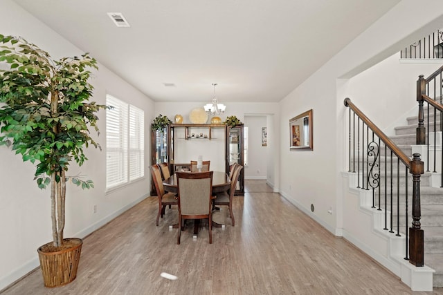 dining space featuring light hardwood / wood-style flooring and an inviting chandelier