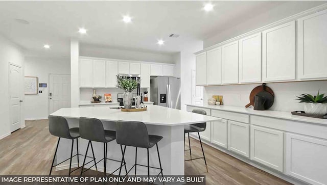 kitchen with stainless steel refrigerator with ice dispenser, light wood-type flooring, white cabinetry, and a kitchen island