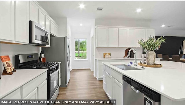 kitchen with white cabinets, sink, an island with sink, wood-type flooring, and stainless steel appliances