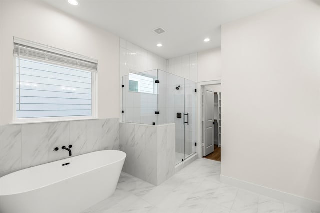 bathroom featuring plenty of natural light, tile walls, and plus walk in shower