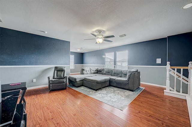 living room with hardwood / wood-style flooring, ceiling fan, and a textured ceiling