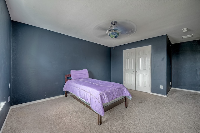 carpeted bedroom with a textured ceiling, a closet, and ceiling fan