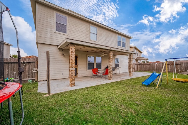 rear view of property with a playground, a patio area, a yard, and a trampoline