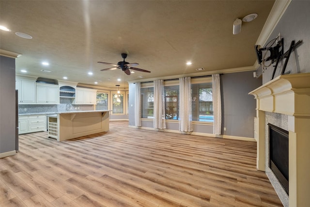 kitchen with white cabinets, decorative backsplash, light wood-type flooring, a kitchen island, and a kitchen bar