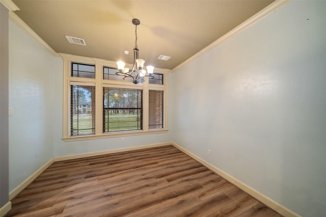 unfurnished dining area featuring hardwood / wood-style flooring, an inviting chandelier, and ornamental molding