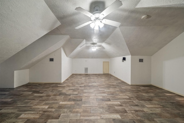 additional living space featuring a textured ceiling, ceiling fan, dark wood-type flooring, and vaulted ceiling