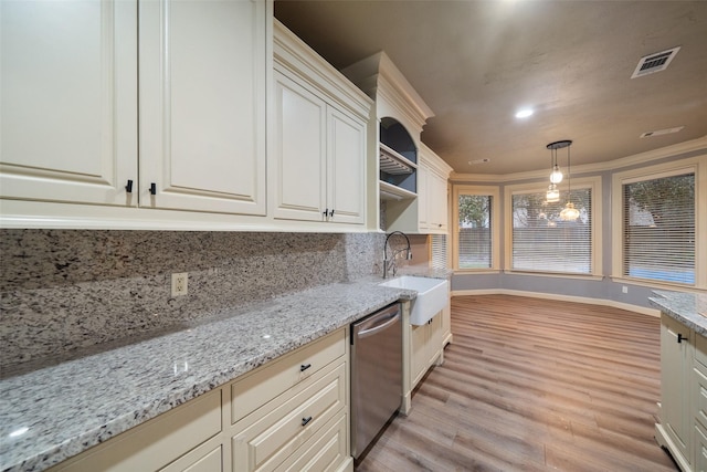 kitchen with stainless steel dishwasher, light stone counters, sink, pendant lighting, and light hardwood / wood-style floors