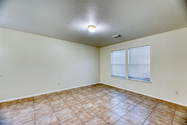 empty room featuring light tile patterned floors and a textured ceiling