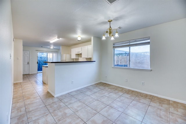 kitchen with kitchen peninsula, decorative light fixtures, an inviting chandelier, white cabinets, and white fridge