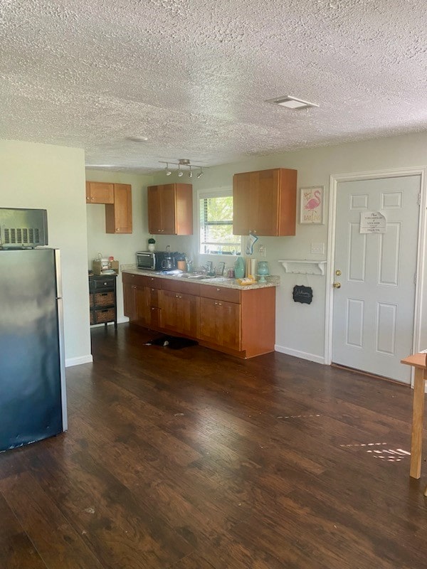 kitchen featuring dark wood-type flooring, a textured ceiling, and appliances with stainless steel finishes