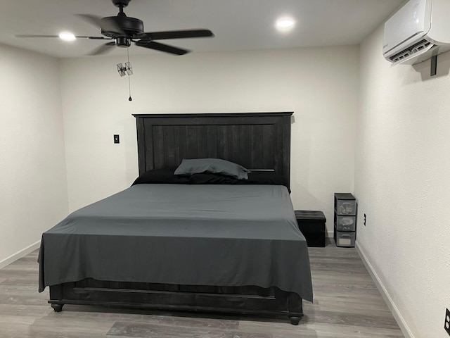 bedroom with ceiling fan, hardwood / wood-style floors, and an AC wall unit