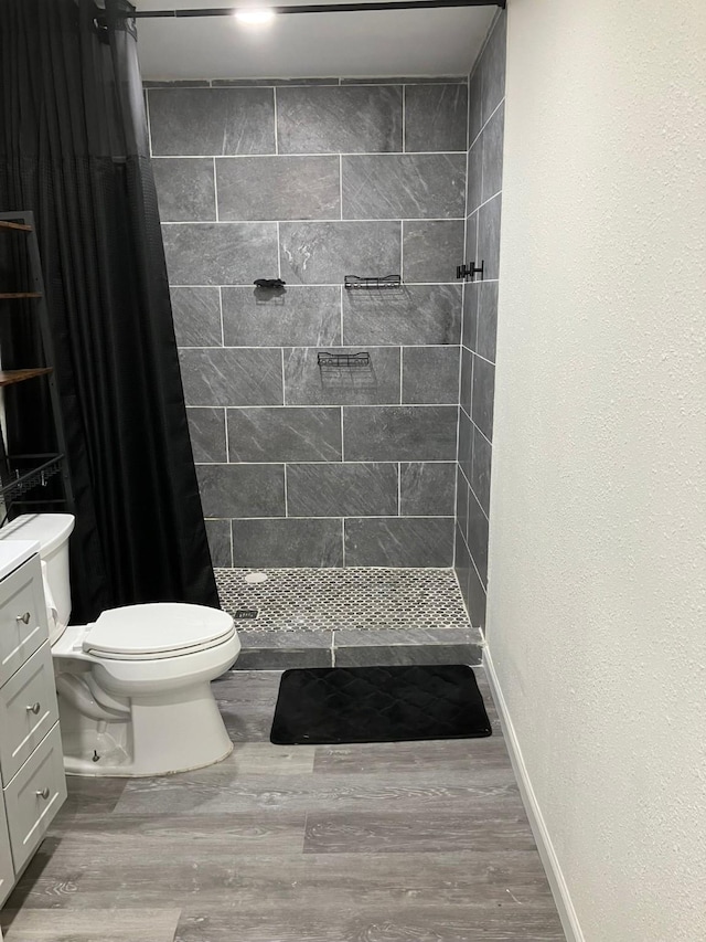 bathroom with hardwood / wood-style flooring, vanity, a shower with shower curtain, and toilet