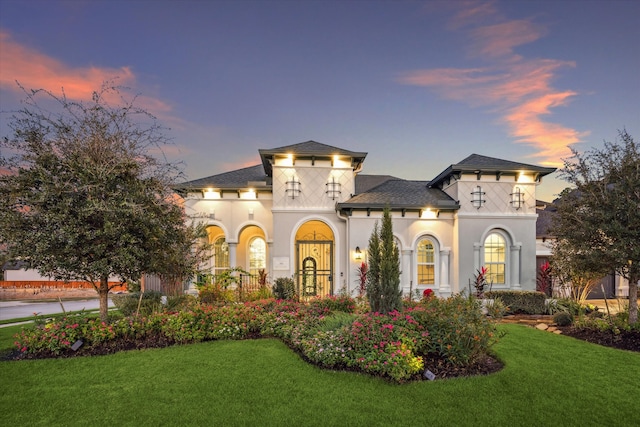 view of front of property featuring a lawn and a balcony