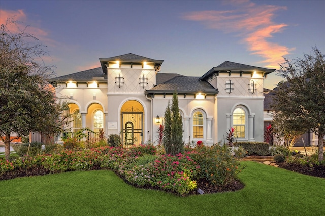 view of front of house featuring a balcony and a lawn