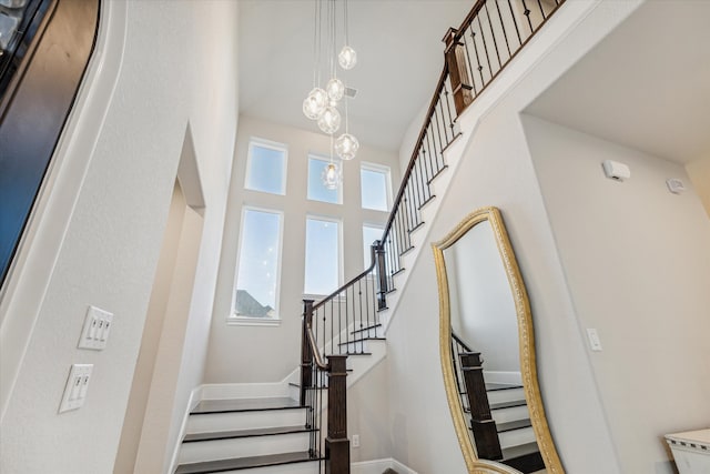 staircase featuring a high ceiling and a notable chandelier