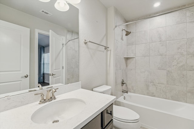 full bathroom featuring tiled shower / bath combo, toilet, and vanity