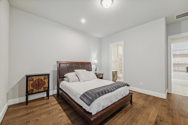 bedroom featuring ensuite bathroom and dark hardwood / wood-style floors